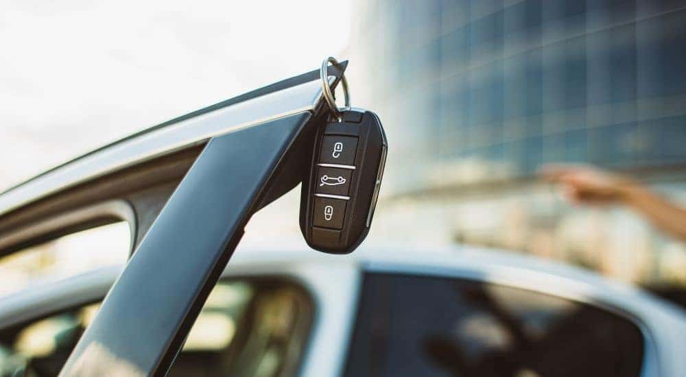 A key fob is shown hanging on an open car door.